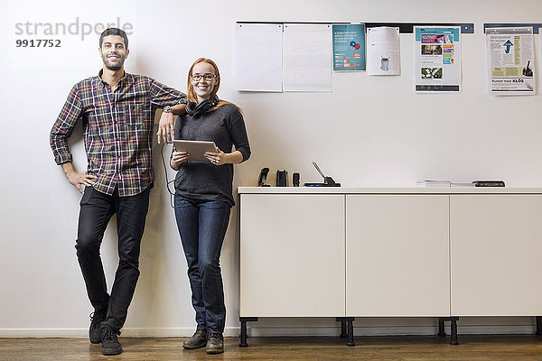 Vollständiges Portrait von lächelnden Geschäftskollegen am Sideboard im Kreativbüro