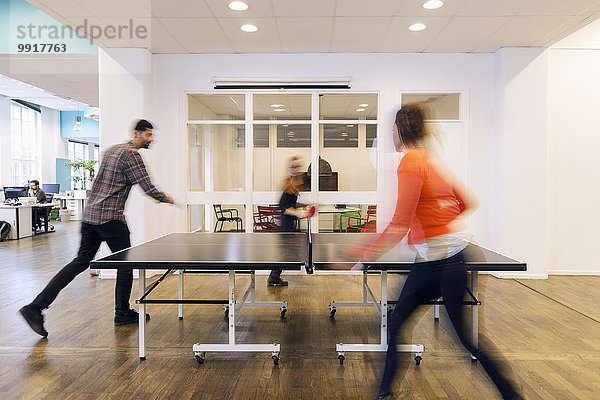 Verschwommene Bewegungen von Geschäftsleuten beim Tischtennisspielen im Kreativbüro