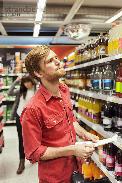 Mann mit Liste beim Einkaufen im Supermarkt