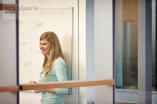 Geschäftsfrau präsentiert Ideen auf Whiteboard im Büro