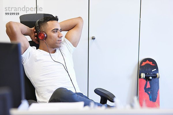 Jungunternehmer beim Entspannen und Hören von Kopfhörern im Büro