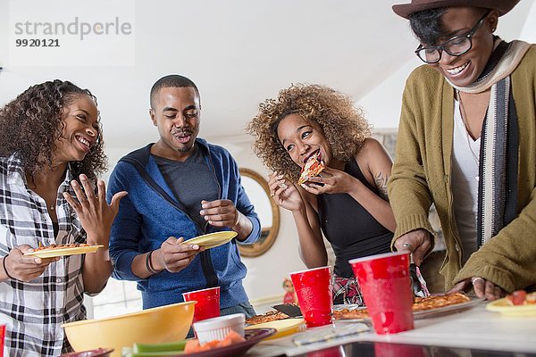 Vier erwachsene Freunde beim Plaudern und Essen in der Küche