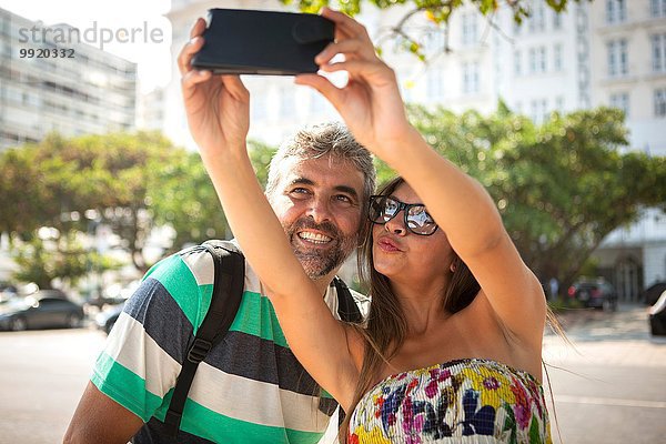 Junge Frau und reifer Mann mit Smartphone Selfie  Copacabana  Rio De Janeiro  Brasilien