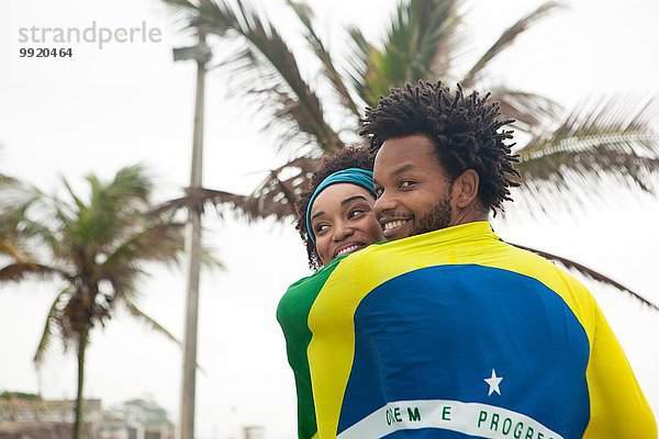 Rückansicht des Paares in brasilianischer Flagge am Strand von Ipanema  Rio De Janeiro  Brasilien