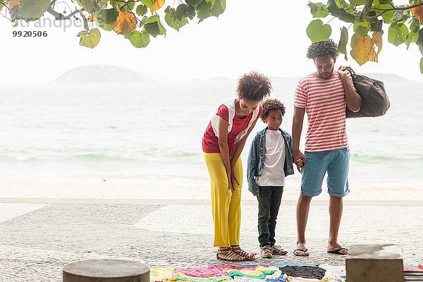 Paar und Sohn wählen Kleidung vom Bürgersteig  Ipanema Strand  Rio De Janeiro  Brasilien