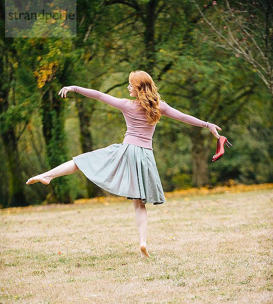Rückansicht der jungen Tänzerin mit roten High Heels im Park