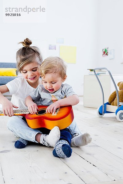 Geschwister spielen zu Hause Spielzeuggitarre