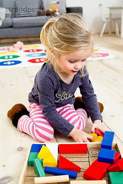 Mädchen beim Spielen mit Bausteinen zu Hause