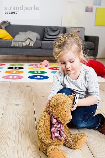 Mädchen spielt mit Teddybär zu Hause