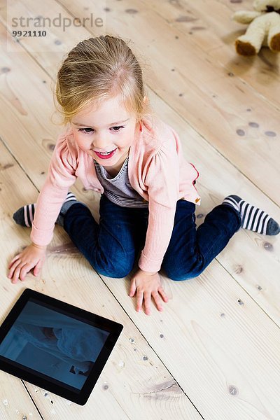 Mädchen mit digitalem Tablett auf Holzboden