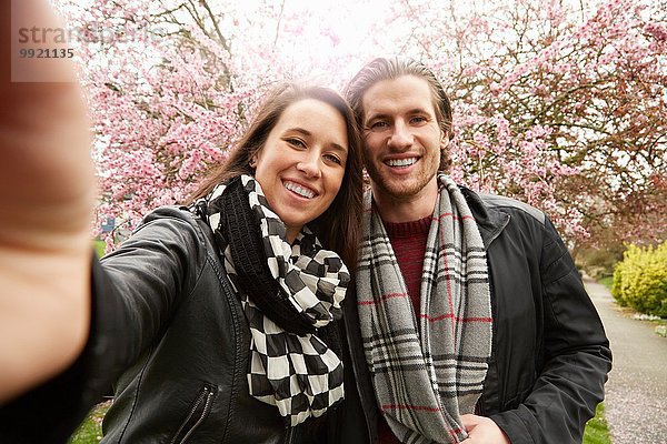 Junges Paar posiert für Selfie mit Blüte im Park