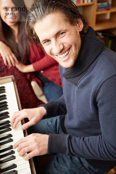 Porträt eines jungen Mannes  der für eine Freundin Klavier spielt
