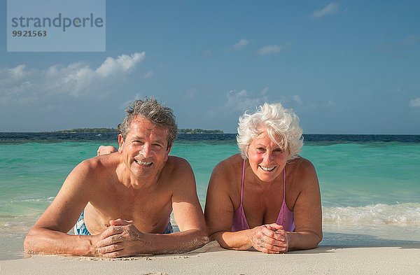Seniorenpaar am Strand liegend  Malediven