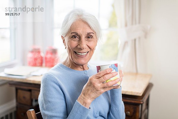 Porträt der lächelnden Seniorin zu Hause mit Pokal