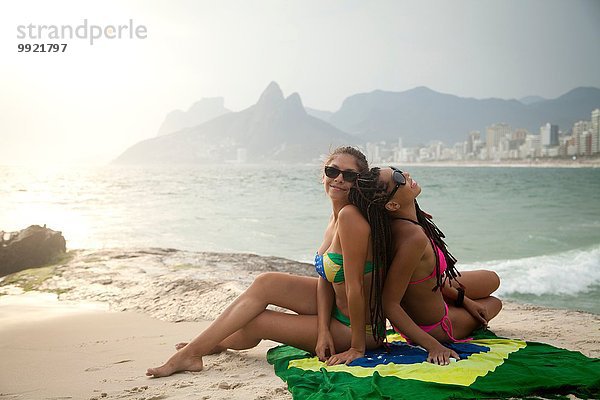 Porträt zweier junger Frauen auf brasilianischer Flagge  Strand von Ipanema  Rio De Janeiro  Brasilien