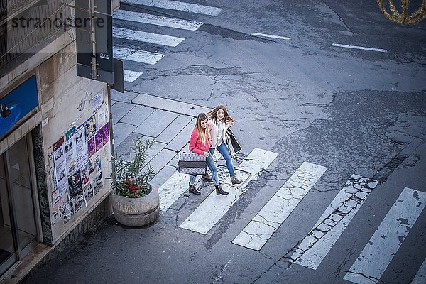 Hochwinkelansicht von zwei Freundinnen auf Pelikanüberquerung