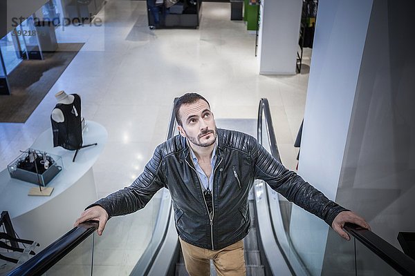 Mann bewegt sich auf Rolltreppe im Einkaufszentrum