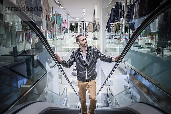 Mittlerer Erwachsener Mann bewegt sich auf Rolltreppe im Einkaufszentrum
