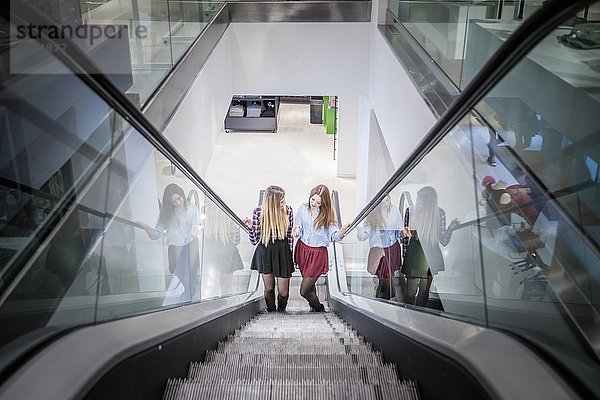 Zwei Freundinnen auf der Rolltreppe im Einkaufszentrum