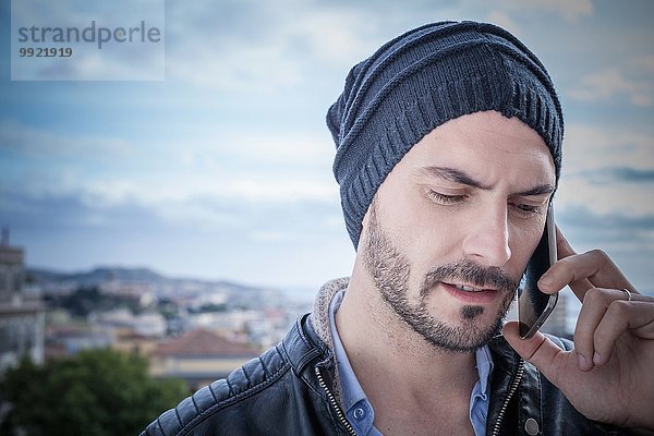 Nahaufnahme eines Mannes auf dem Dach  der auf dem Smartphone spricht  Cagliari  Sardinien  Italien