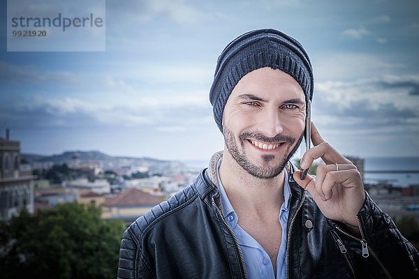 Porträt eines Mannes auf dem Dach  der auf Smartphones spricht  Cagliari  Sardinien  Italien