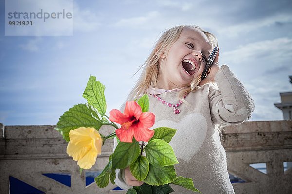 Junges Mädchen mit Blumen lachend und plaudernd auf Smartphone  Cagliari  Sardinien  Italien