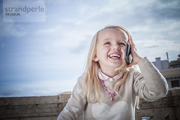Junges Mädchen lacht und plaudert auf dem Smartphone  Cagliari  Sardinien  Italien