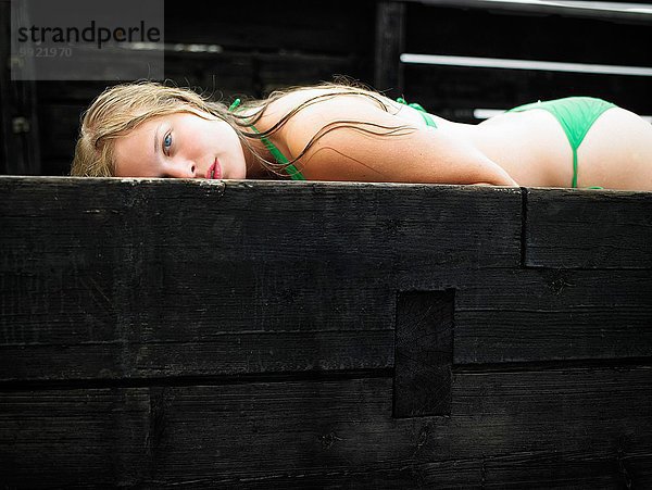 Porträt eines Mädchens im Bikini auf dem Pier liegend