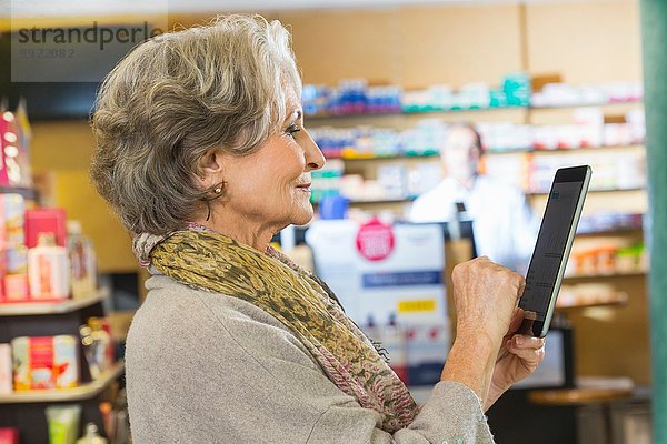Seniorin benutzt digitale Tabletten  um Medikamente online in der Apotheke zu prüfen