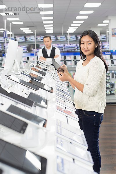 Porträt einer jungen Shopperin beim Durchblättern von digitalen Tabletts im Elektronikgeschäft