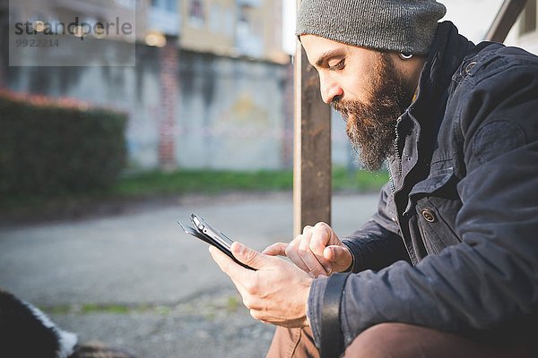 Mittlerer Erwachsener Mann  im Freien sitzend  mit digitalem Tablett