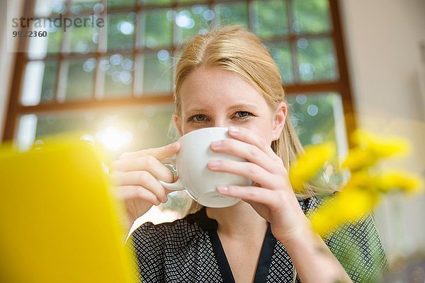 Junge Frau sitzt im Café  trinkt Kaffee  benutzt Laptop