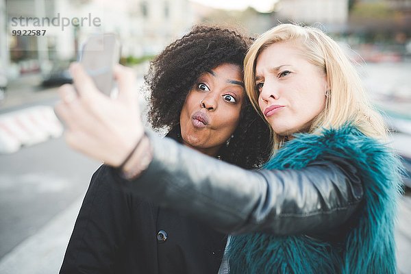 Zwei junge Frauen ziehen Gesichter für Smartphone Selfie  Comer See  Comer See  Italien