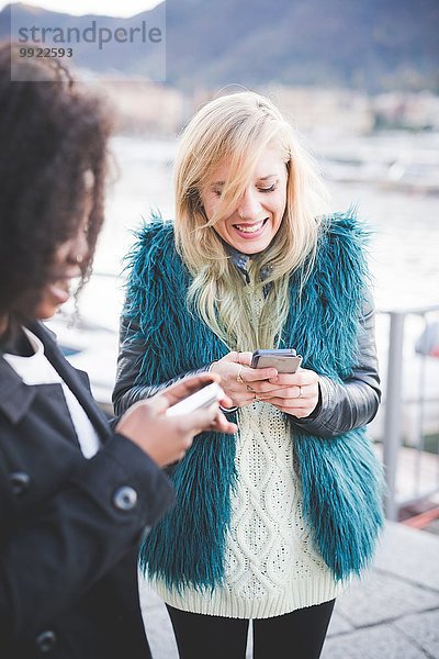 Zwei junge Frauen texten auf Smartphones am Comer See  Comer See  Italien