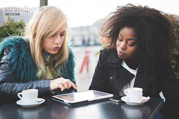 Zwei junge Frauen mit Touchscreen auf digitalem Tablett im Straßencafé  Comer See  Comer See  Italien