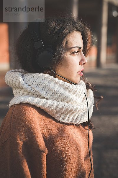 Portrait einer jungen Frau mit Kopfhörer im Park