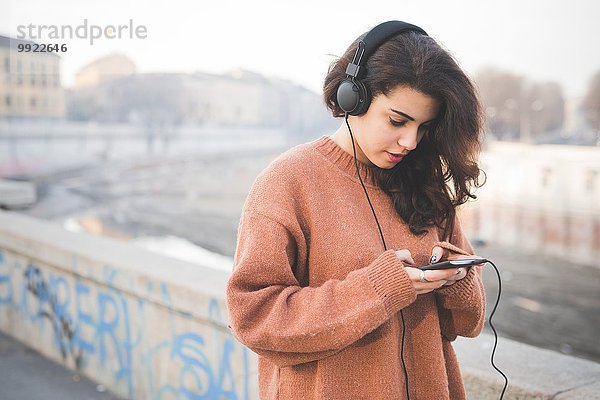 Junge Frau mit Kopfhörer und Musik auf dem Smartphone