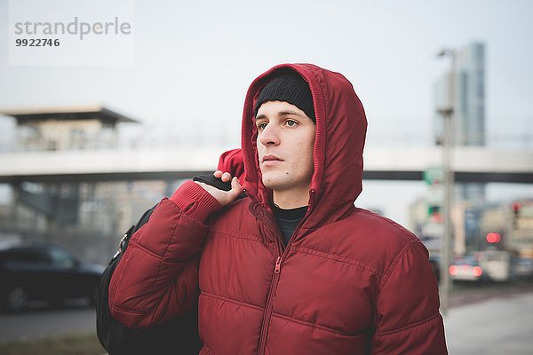 Junger Mann mit rotem Kapuzenanorak auf der Stadtstraße