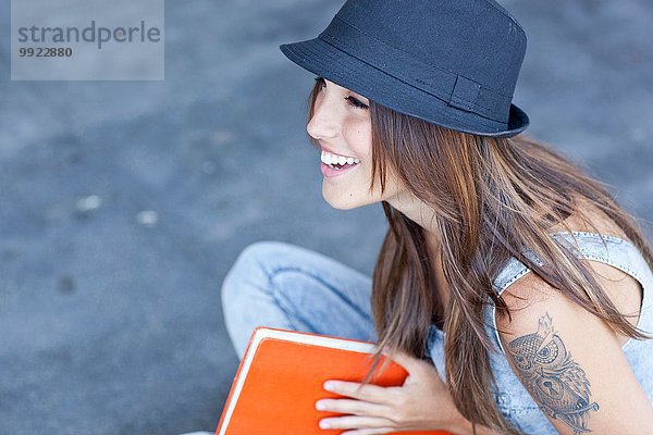 Studentin mit Hut  die ein Buch trägt.