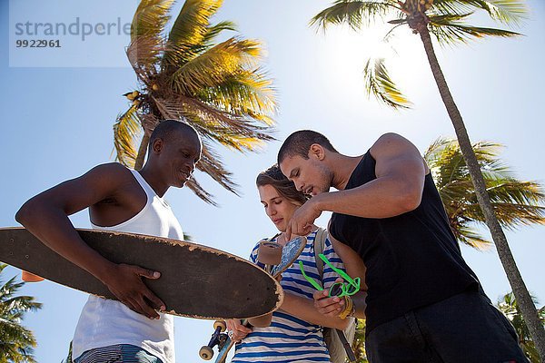 Junger Mann hält Skateboard mit Freunden  niedriger Winkel