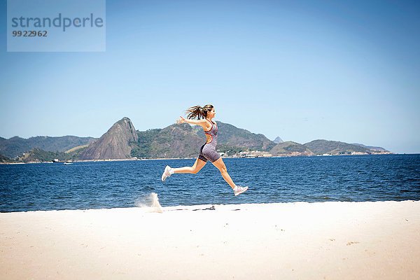 Junge Frau beim Springen am Strand  Rio de Janeiro  Brasilien