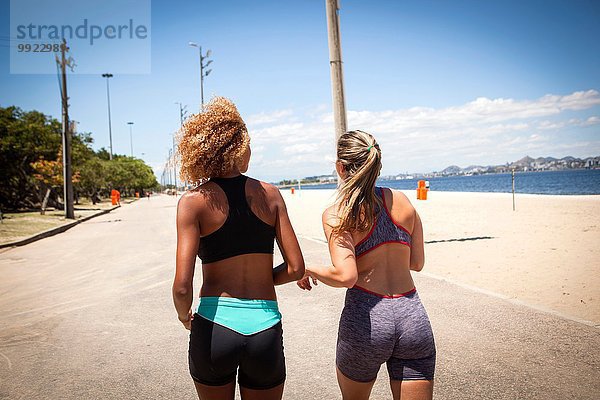Zwei junge Frauen beim Joggen am Strand  Rückansicht