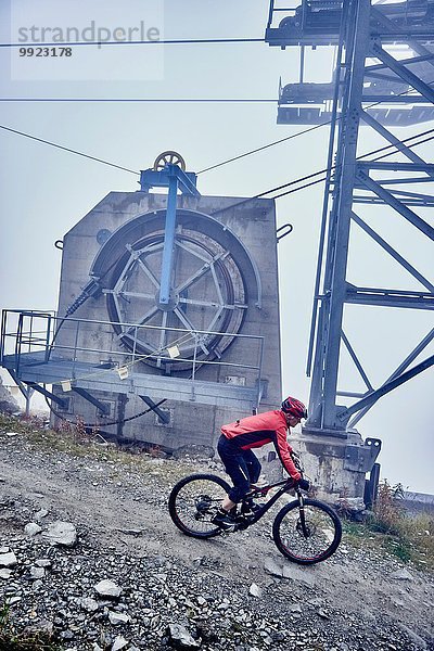 Erwachsener Mann Mountainbiken an der Seilbahn vorbei  Wallis  Schweiz