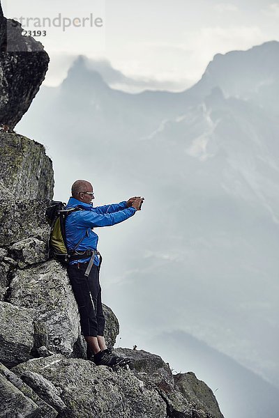 Reifer Mann auf Felsen beim Fotografieren  Wallis  Schweiz