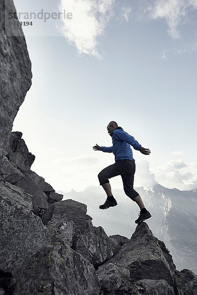 Erwachsener Mann  der auf Felsen springt  Wallis  Schweiz