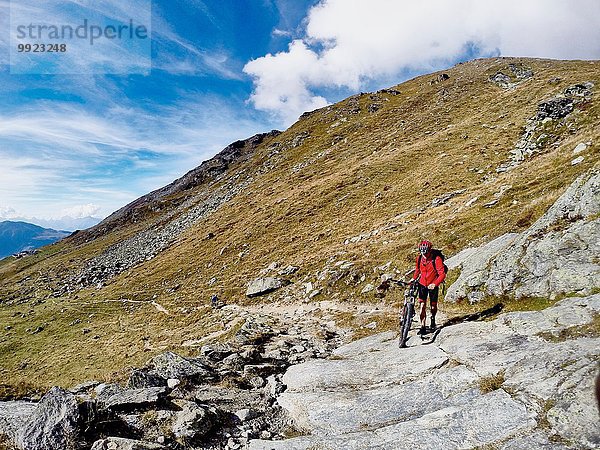 Mountainbiker schieben Fahrrad über Felsen  Wallis  Schweiz