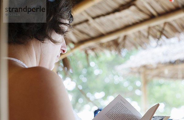 Über die Schulteransicht der lesenden Frau vor der Strandhütte  Kradan  Thailand