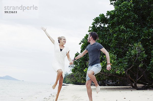 Junges Paar beim Springen und Toben am Strand  Kradan  Thailand