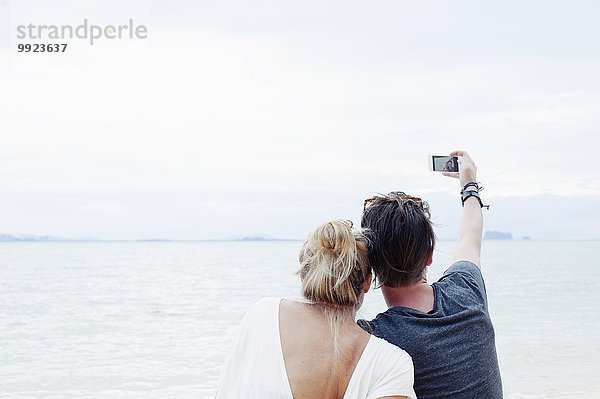 Rückansicht des jungen Paares mit Smartphone Selfie am Strand  Kradan  Thailand