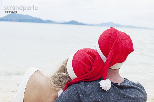 Rückansicht eines jungen Paares mit Weihnachtsmützen am Strand  Kradan  Thailand